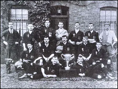 The Thames Iron Works team in 1896 with the West Ham Charity Cup. Back row (left to right): Arnold Hills, French, Graham, Francis Payne, John Woods, William Hickman and Tom Robinson (trainer). Centre; William Chamberlain, George Sage, William Faram, William Chapman, William Barnes. Front; Johnny Stewart, Thomas Freeman.