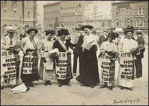 Mabel Capper (second from left) Mary Gawthorpe (wearing all black) and Patricia Woodlock (far right) selling Votes for Women in Manchester on 20th June, 1908.