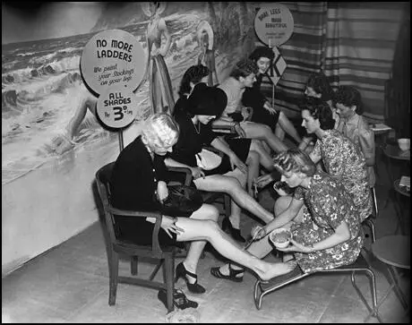 Customers save their ration coupons by having "stockings" painted on their legs (1942)